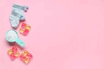 Scoop with laundry detergent, gel capsule and baby socks on pink background