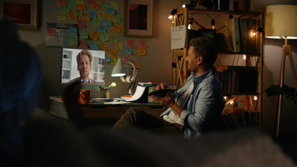 Friends enjoying video chat in cozy evening. Cheerful guys talking by web cam