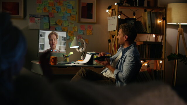 Friends enjoying video chat in cozy evening. Cheerful guys talking by web cam