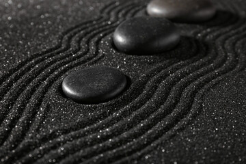 Stones on dark sand with lines in Japanese rock garden. Zen concept