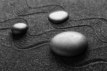 Spa stones on black sand with lines, closeup. Zen concept