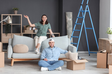 Happy young couple sitting in room on moving day