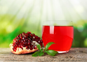 Delicious ripe pomegranate and juice on wooden table against blurred background
