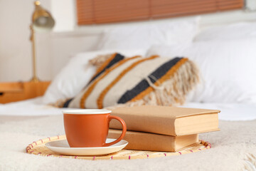 Cup of tea and books on bed in bedroom, closeup
