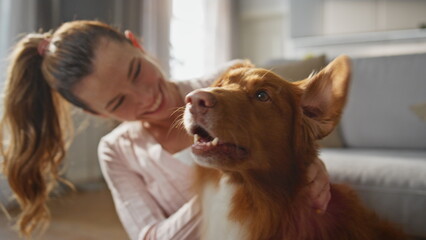 Girl scratching lovely dog behind ears sitting home floor together close up.