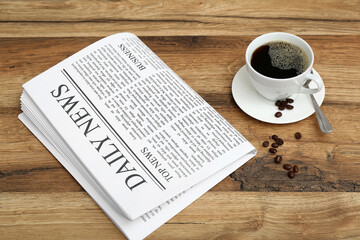 Newspaper with cup of coffee and beans on wooden background