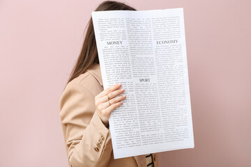 Woman with newspaper on pink background