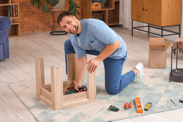 Young man with screwdriver assembling wooden table at home