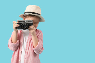 Obraz premium Cute little boy with camera taking picture on blue background. Travel concept