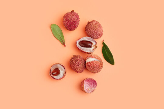 Tasty litchi fruit and leaves on beige background