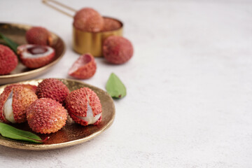 Plate with tasty litchi fruit on light background, closeup