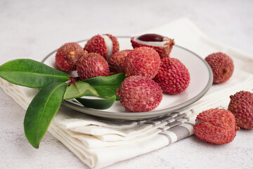Plate with delicious litchi fruit on light background, closeup