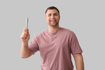 Handsome young happy diabetic man with lancet pen on grey background
