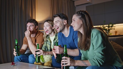 Smiling buddies watching movie at night home couch. Happy friends looking tv