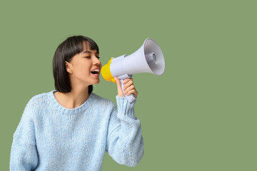 Young woman with megaphone on green background