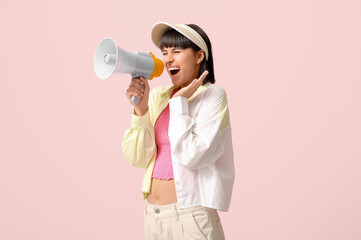 Screaming young woman with megaphone  on pink background