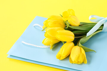 Paper shopping bag with tulips on yellow background