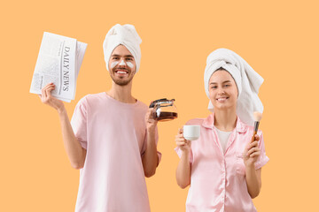 Young loving couple with newspaper and coffee after shower on beige background