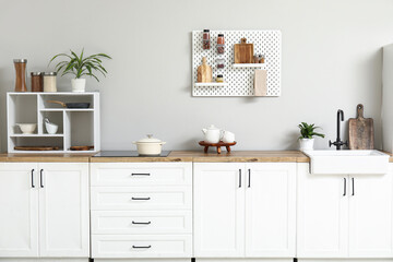 Fototapeta na wymiar Stylish light kitchen with pegboard and kitchenware