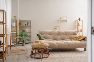 Interior of white living room with beige sofa, coffee table and shelving unit