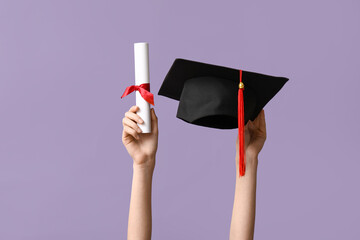 Female hands with graduation hat and diploma on lilac background