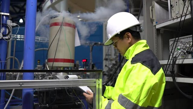 Engineer checks nitrogen liquid in large industrial factory,Research assistants prepare machines to conduct scientific experiments.