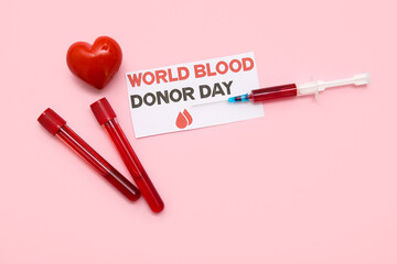 Composition with test tubes, syringe, heart and paper sheet with text WORLD BLOOD DONOR DAY on pink...