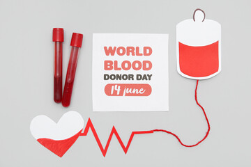 Composition with sign WORLD BLOOD DONOR DAY 14 JUNE and test tubes on grey background