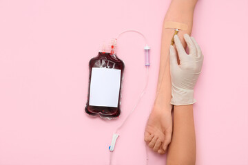 Female hands with blood pack for transfusion on pink background