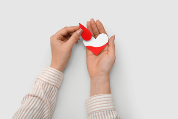 Female hands holding paper drop and heart on white background. World blood donor day.
