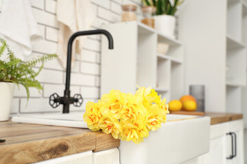 Beautiful bouquet of daffodils in sink in kitchen