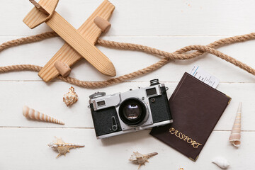 Composition with photo camera, passport, toy plane and seashells on light wooden background