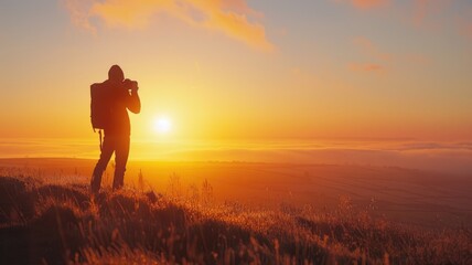 Fototapeta premium Silhouette of person taking photo at sunset in grassy field