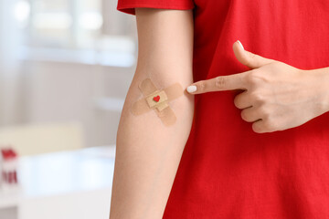 Female blood donor pointing at applied patch in clinic, closeup
