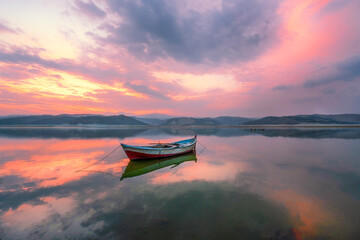 boats waiting in the reflective water clouds in the sky sunset colors