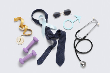 Tie, medal, sunglasses, male sign and light blue ribbon on grey background. Prostate cancer...