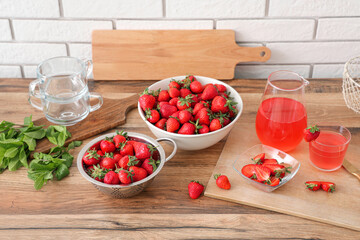 Bowl with tasty strawberries and juice on counter in kitchen