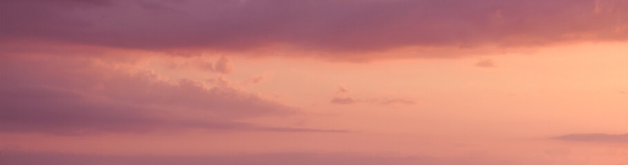 Panoramic purple pink yellow orange golden sky with clouds. Beautiful sunset summer nature soft romance peaceful and calm sky. Cloudscape background. 