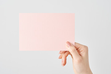 ピンク色の紙を持つ女性の手元