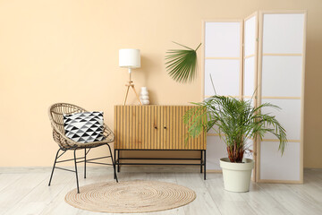 Interior of room with folding screen, commode and chair near beige wall