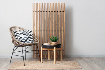 Interior of room with wooden folding screen, chair and coffee table near white wall