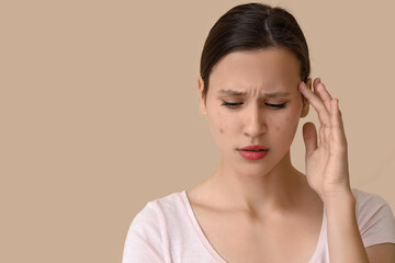 Beautiful young worried woman with acne problem on beige background