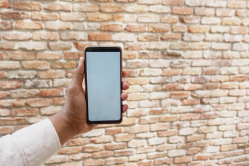 Mobile phone in hand on brick background