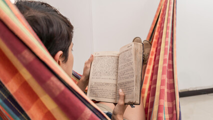 woman reading a book calmly at home in the hammock