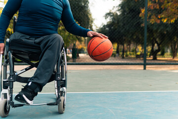 Naklejka premium hand of adult athlete practicing basketball and bouncing the ball in a wheelchair on a court