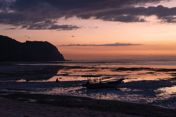 Female woman sat on the beach in low tide at sunset.