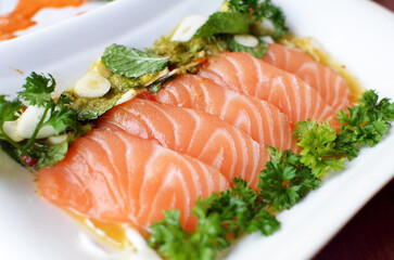 sliced salmon with parsley leaf in the white plate isolated on white background