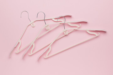 Minimalist Pink Background with Three White Hangers for Clothing Organization and Fashion Display