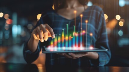 A person interacting with a digital tablet displaying colorful data graphs, representing technology and business analytics at night.