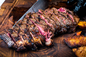 Top view of ultra-thin slices of rare, large roast beef on an Australian tomahawk steak. Revealing pink flesh Beautiful golden brown shell Served on a black butcher knife on the table, yes.